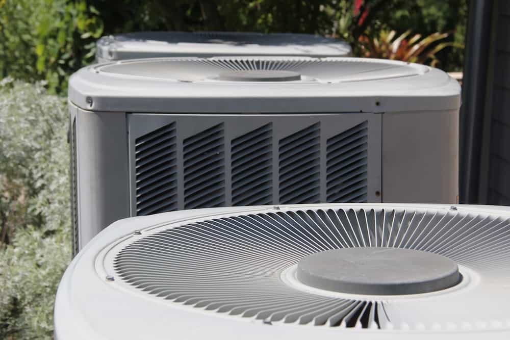 Close-up view of three outdoor air conditioning units with visible fan tops and vented side panels.
